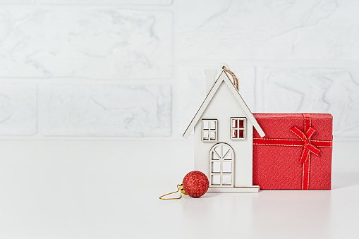 White House - toy, red gift box on a light background. Copy space. Give or buy a cottage for Christmas.