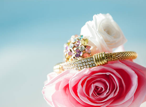 Autumn leaves, three roses, gold jewelry chains and bracelets lie on a wooden background.\