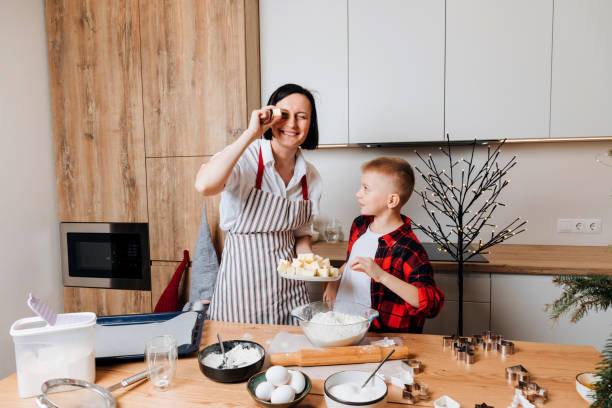 Mom and son are kneading dough for cookies at a wooden table in the kitchen. Cooking desserts at home. Joint activities with children stock photo
