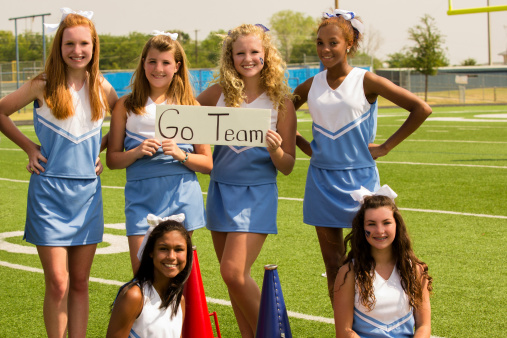 High school cheerleaders hold 'go team' sign in preparation for Friday night's football game. 