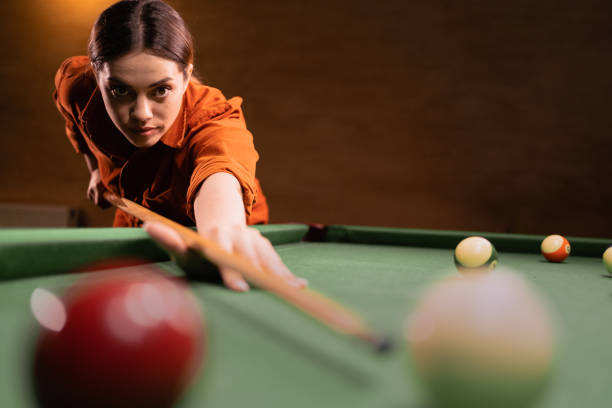 istock Female billiard player using the cue stick while playing billiard at the club. Playing billiards 1872372224
