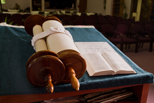 Jewish Traditions: A serene moment of study and reflection with a Torah scroll in a warmly lit synagogue in Fort Wayne, Indiana.