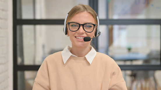 Portrait of Smiling Young Woman with Headset in Call Center