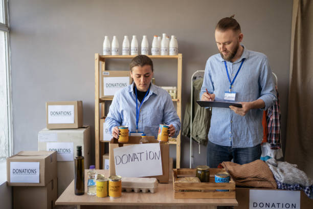 istock Two people working in charitable foundation. Happy volunteer at workplace with donation food box. Volunteers sort donations during food drive 1872377005