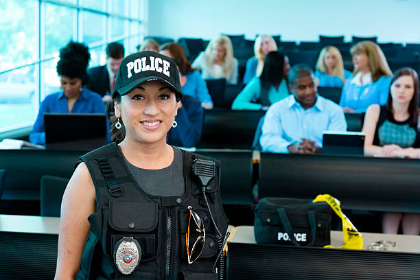 Law:  Policewoman speaks to police cadets. Policewoman speaks to police cadets in lecture hall;  or policewoman gives safety presentation to local community. officer military rank stock pictures, royalty-free photos & images