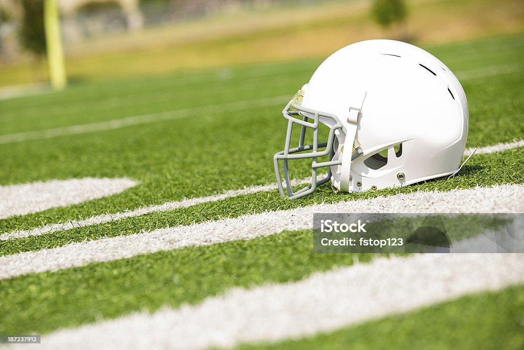 Sports:  Football helmet on playing field.  Yard markers foreground. Football sports helmet on playing field with field goal in background.  Yard markers in foreground. Football Helmet Stock Photo