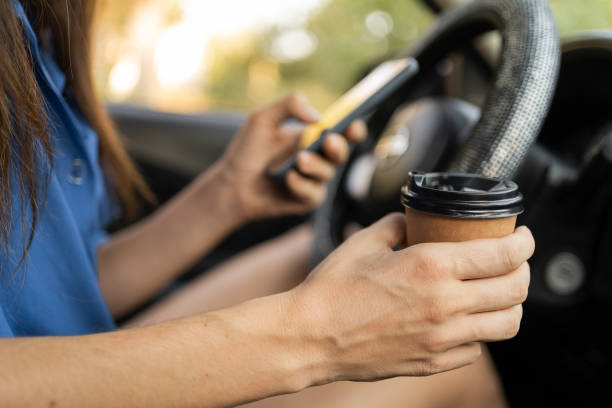 istock Attractive woman drinking coffee and using mobile phone while driving the car. Transportation and vehicle 1872387009