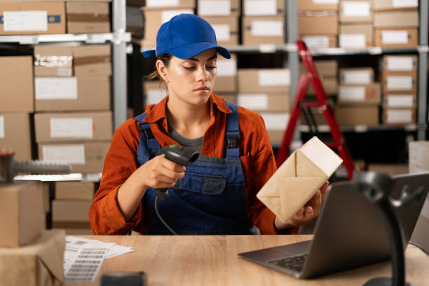istock Female seller worker using scanner scanning parcel barcode tag, post shipping box, orders in dropshipping delivery service. Warehouse concept 1872391223