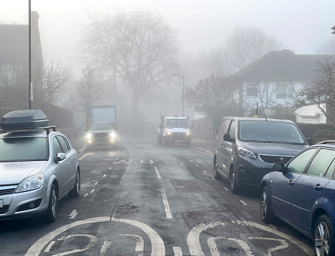 Suburban foggy road with parked cars