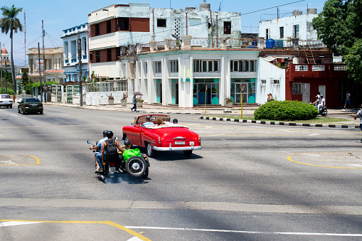Havana City, Cuba - August 25, 2018: A vintage car and motorcycle on a city avenue.