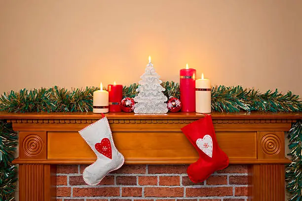 Christmas stockings hanging over a fireplace with candles on the mantlepiece