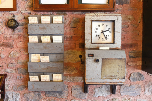 Old time clock at a work place together with time card holding shelves.