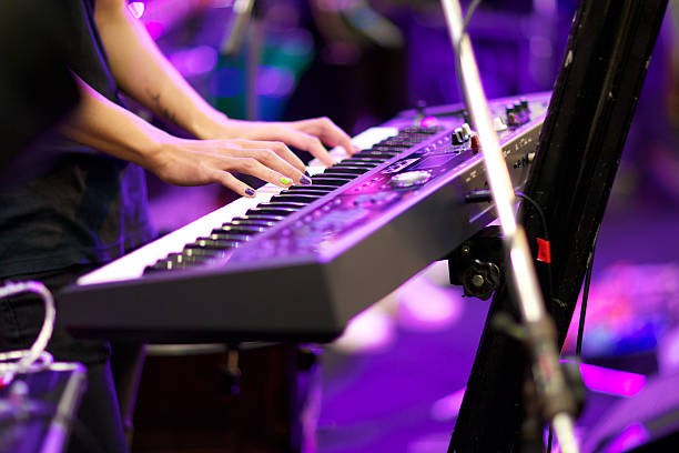Woman's hands playing a keyboard in concert hands of musician playing keyboard in concert with shallow depth of field, focus on right hand rocker nails stock pictures, royalty-free photos & images