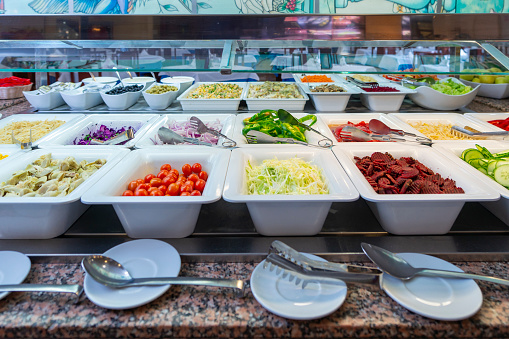 Sorted fresh salads displayed on a buffet in restaurant.