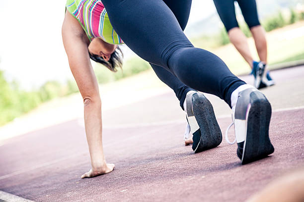 Sporty woman running in the morning sunlight crossing a bridge. Close up on the sports shoes.
