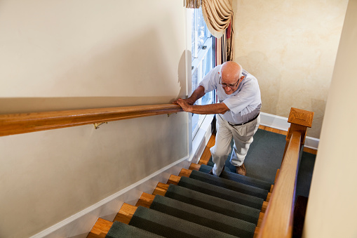 Senior man (80s) climbing staircase.