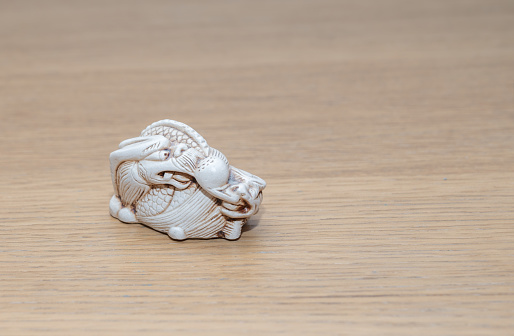 Netsuke of dragon on wooden background. Asian dragon. Symbol of the Dragon New Year. Asian culture.