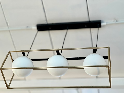 Illuminated modern three metal cage hanging lamps  on white ceiling inside