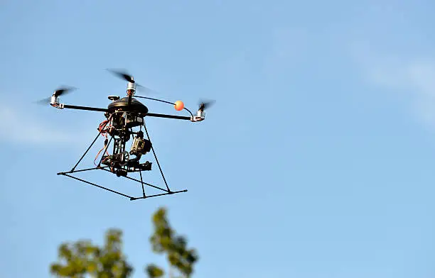 Small camera mounted on a remote-control helicopter in flight.