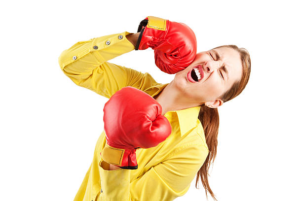 Woman Punching Herself In The Face A woman wearing boxing gloves and punching herself in the face. low self esteem stock pictures, royalty-free photos & images