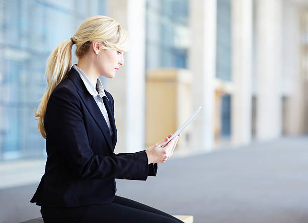 Familiarising herself with the business project A beautiful young businesswoman working on her digital tablet in the office lobby familiarising stock pictures, royalty-free photos & images