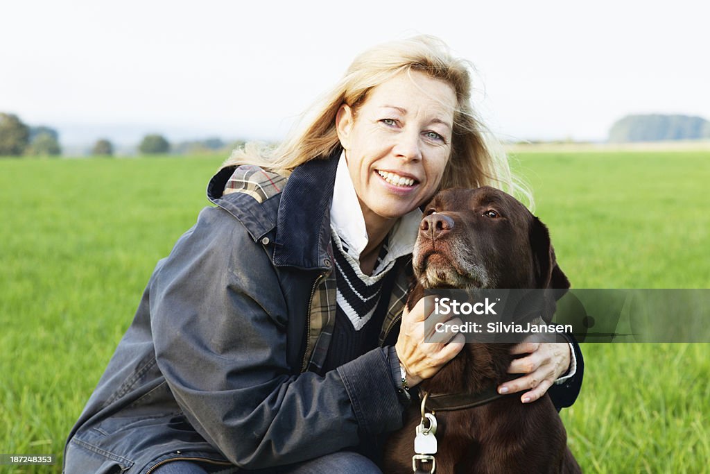 woman embracing  dog healthy lifestyle beautiful mature woman with long blonde hair embracing  her dog on  a green meadow 40-44 Years Stock Photo