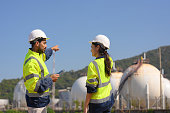 Two chemical engineers consult to prepare a work plan for a refinery storage tank.