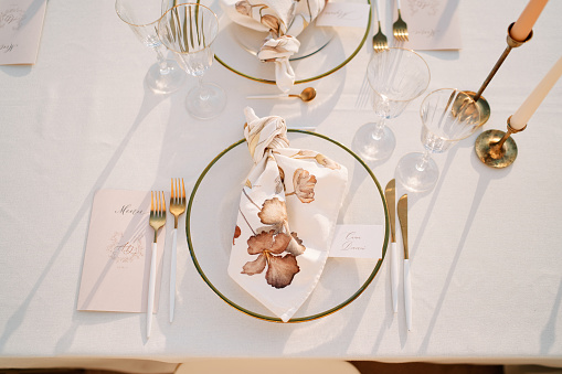 Knotted napkin lies on a plate on a set table near a personalized invitation. High quality photo