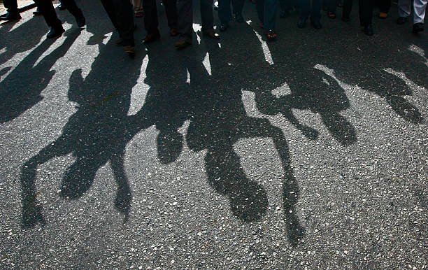 Shadow of Protesters Protesters cast a shadow as they march on a street political rally photos stock pictures, royalty-free photos & images