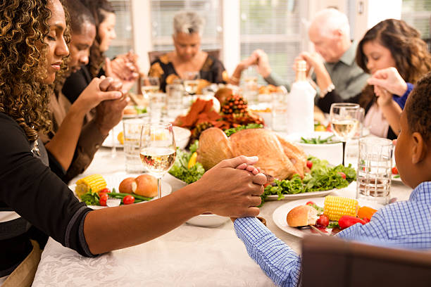 prega di famiglia a tavola del ringraziamento con le mani - thanksgiving table setting autumn foto e immagini stock