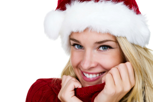 Closeup of a beautiful young woman with a playful expression wearing a santa hat