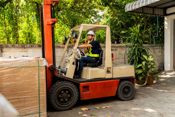 istock Man worker at forklift driver happy working in industry factory logistic ship. Man forklift driver in warehouse area. Forklift driver sitting in vehicle in warehouse. 1872529186