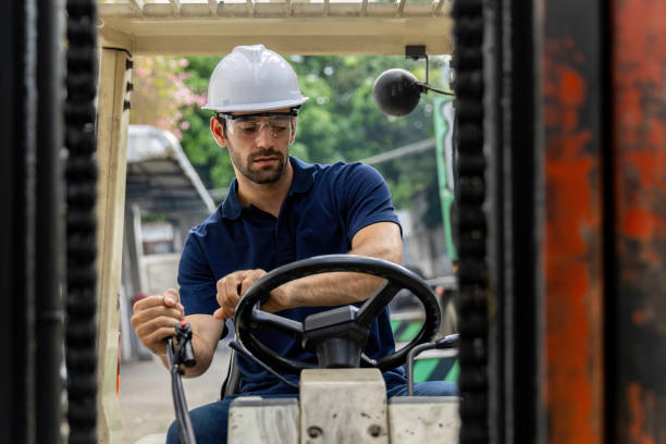 istock Man worker at forklift driver happy working in industry factory logistic ship. Man forklift driver in warehouse area. Forklift driver sitting in vehicle in warehouse. 1872529198