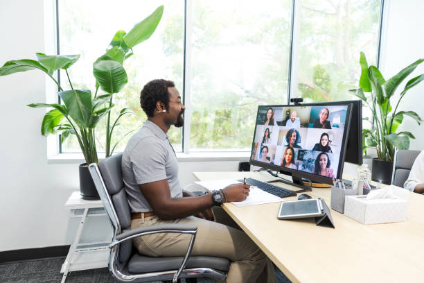 Young adult businessman smiles while meeting with his coworkers virtually