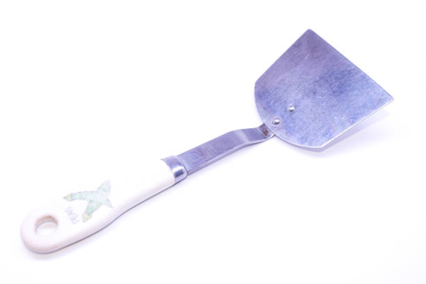 Stainless steel spatula with peas written on the white handle. On isolated white background