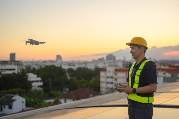 istock Male engineer works installing solar panels on the roof. Engineer or worker working on solar panels or photovoltaic cells on the roof of a business building. 1872547480