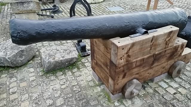Wrought iron wood mounted artillery cannon displayed on British cobblestone pavement
