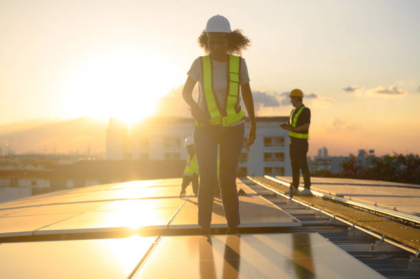 istock Female engineer works installing solar panels on the roof. Engineer or worker working on solar panels or photovoltaic cells on the roof of a business building. 1872557262