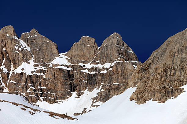 istock Rocks in snow and blue cloudless sky 187256025