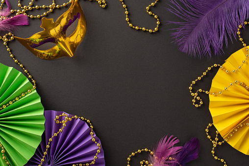 Carnival Glamour Composition: Top-view shot showcasing lavish carnival mask, classic bead necklace, feathered accents, lively paper fans on sleek black surface, leaving space for custom text or promo