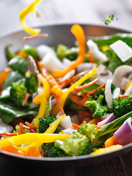 vegetables falling into a stir fry wok. close up photo of vegetables falling into a stir fry wok. Slective Focus stock pictures, royalty-free photos & images