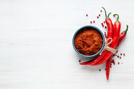 Heap of paprika with sweet bell peppers on light grey table, closeup