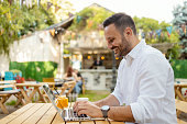 Bearded Man Using Laptop in Outdoor Cafe