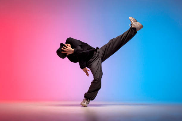 istock young guy dancer in black clothes break dancing in neon lighting, man performs hip hop movement in red blue club 1872627392