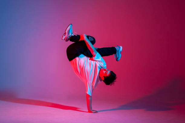 istock young guy dancer is dancing break in neon lighting, male acrobat is doing trick and dance exercise 1872627397