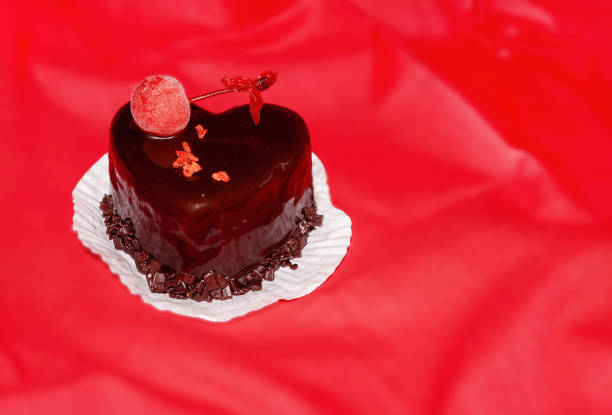 istock Heart-shaped dessert with a berry on top on a red background 1872629536