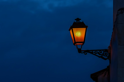 Old street lamp illuminated at sunset