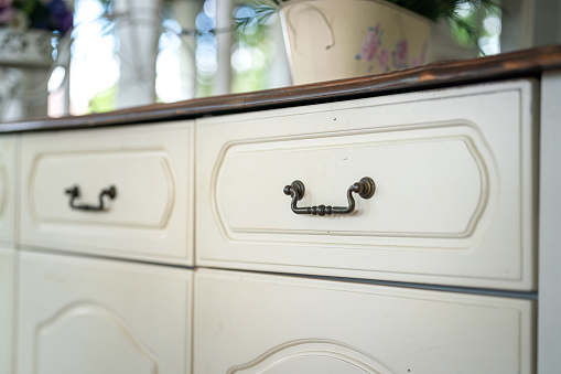 Close-up at iron drawer handle of the classic style cupboard. Interior furniture part and object photo. Selective focus.