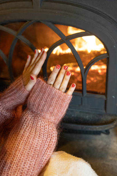 istock Woman's hands warming herself by the fire in fireplace 1872643290