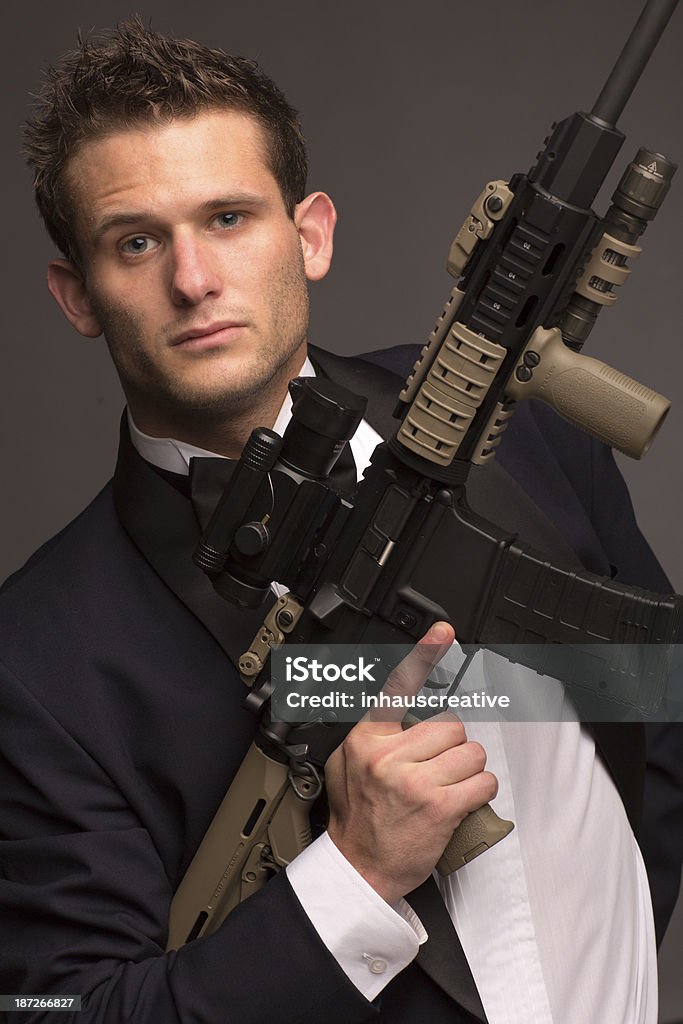 Well Dressed Man with AR 15 Well Dressed Man with AR 15. This stock image has a vertical composition, isolated on gray. 30-39 Years Stock Photo